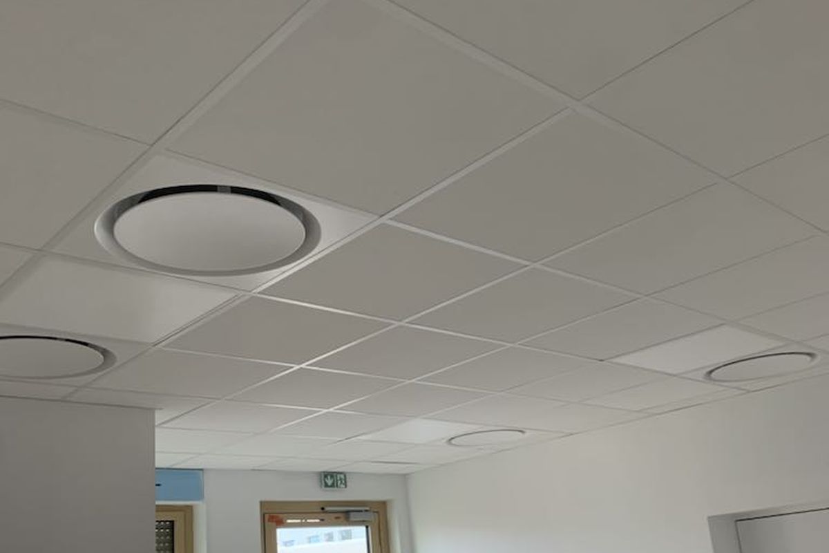 Bouches rondes d’une climatisation gainable intégrées au faux plafond d’un local professionnel