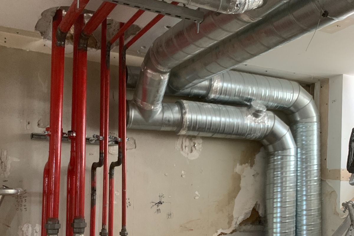 Réseaux en tube acier rouge et gaines de ventilation, en cours de chantier