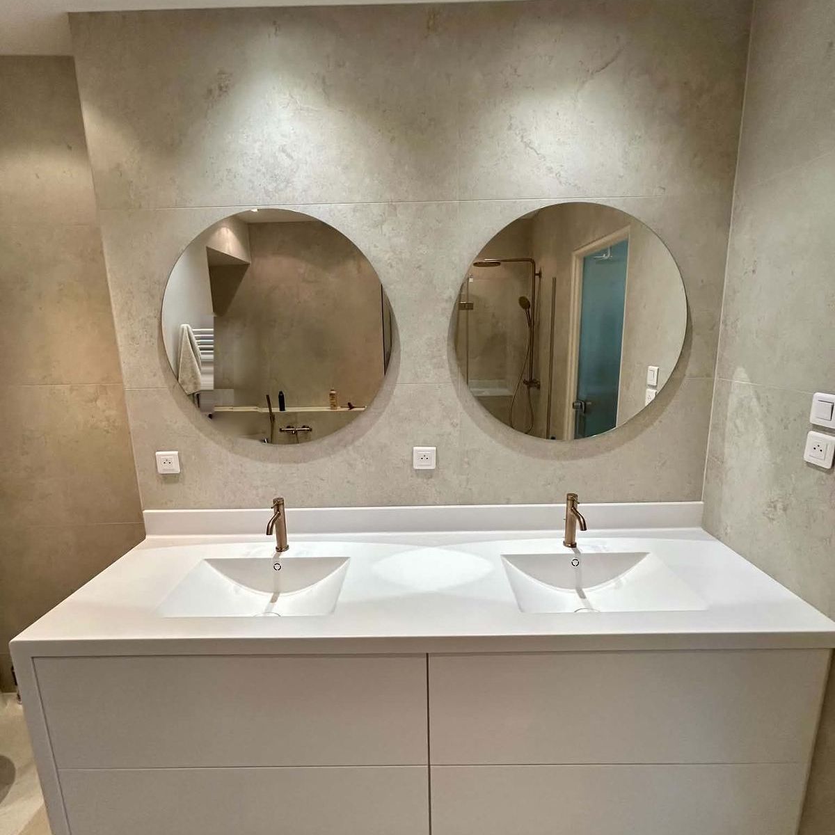 Salle de bain : double vasque blanche, robinetterie cuivrée et miroirs ronds