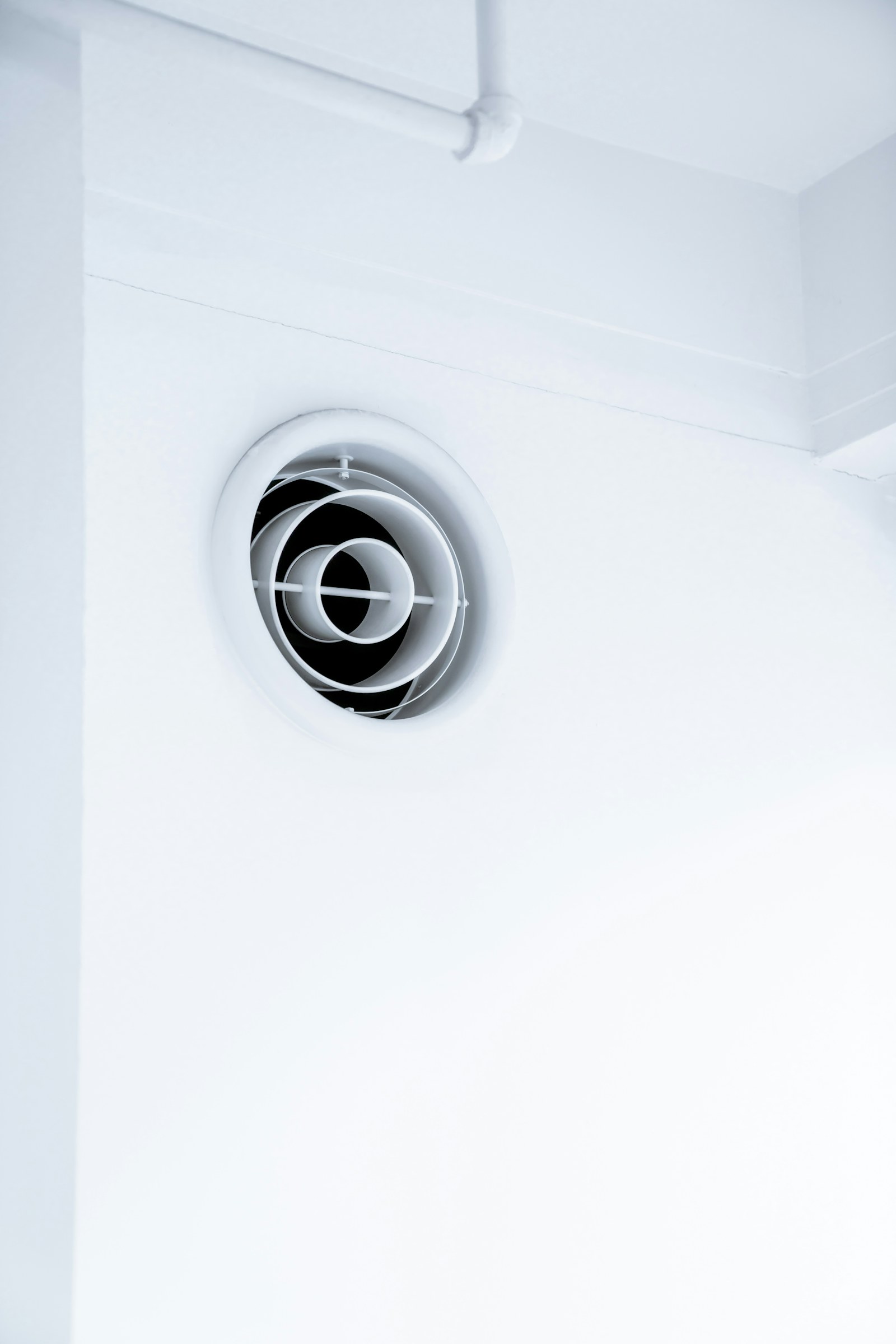 Bouche ronde de ventilation posée en partie haute sur un mur blanc