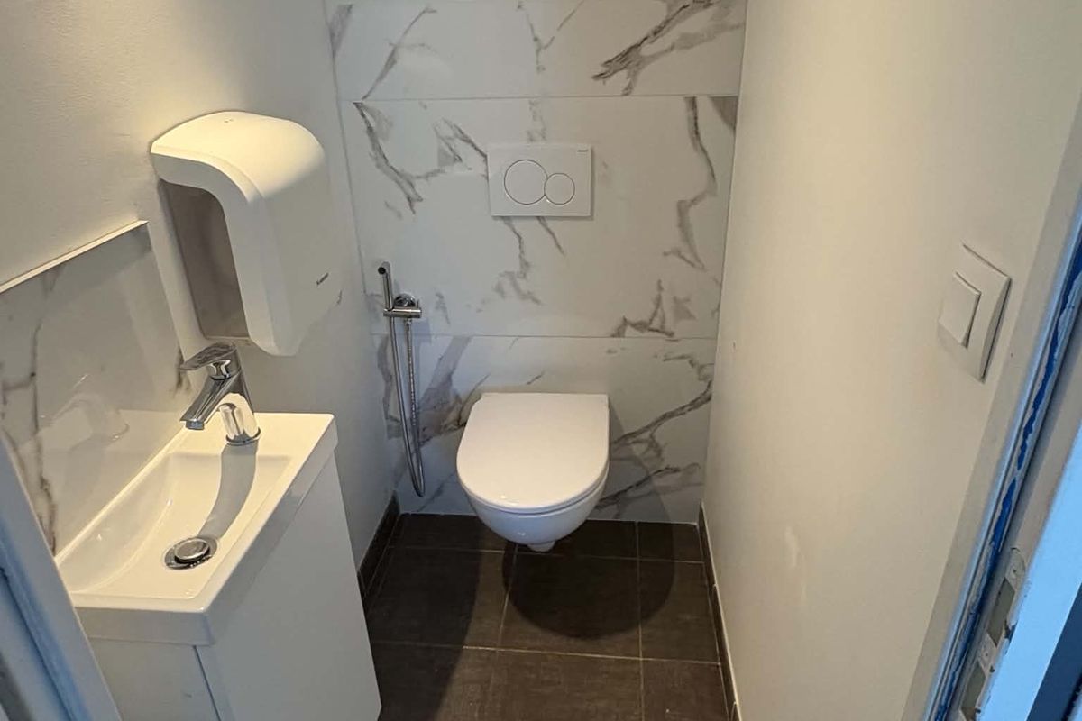 WC suspendu et lave-mains sur mur en carreaux effet marbre